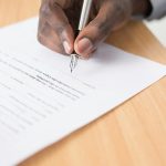 person writing on paper about business contract dispute
