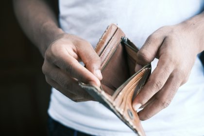 person holding brown leather bifold wallet after overspending.