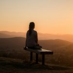 woman sitting on bench over viewing mountain; Rituals
