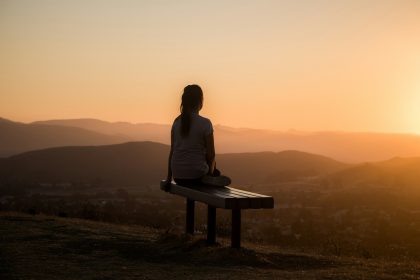 woman sitting on bench over viewing mountain; Rituals