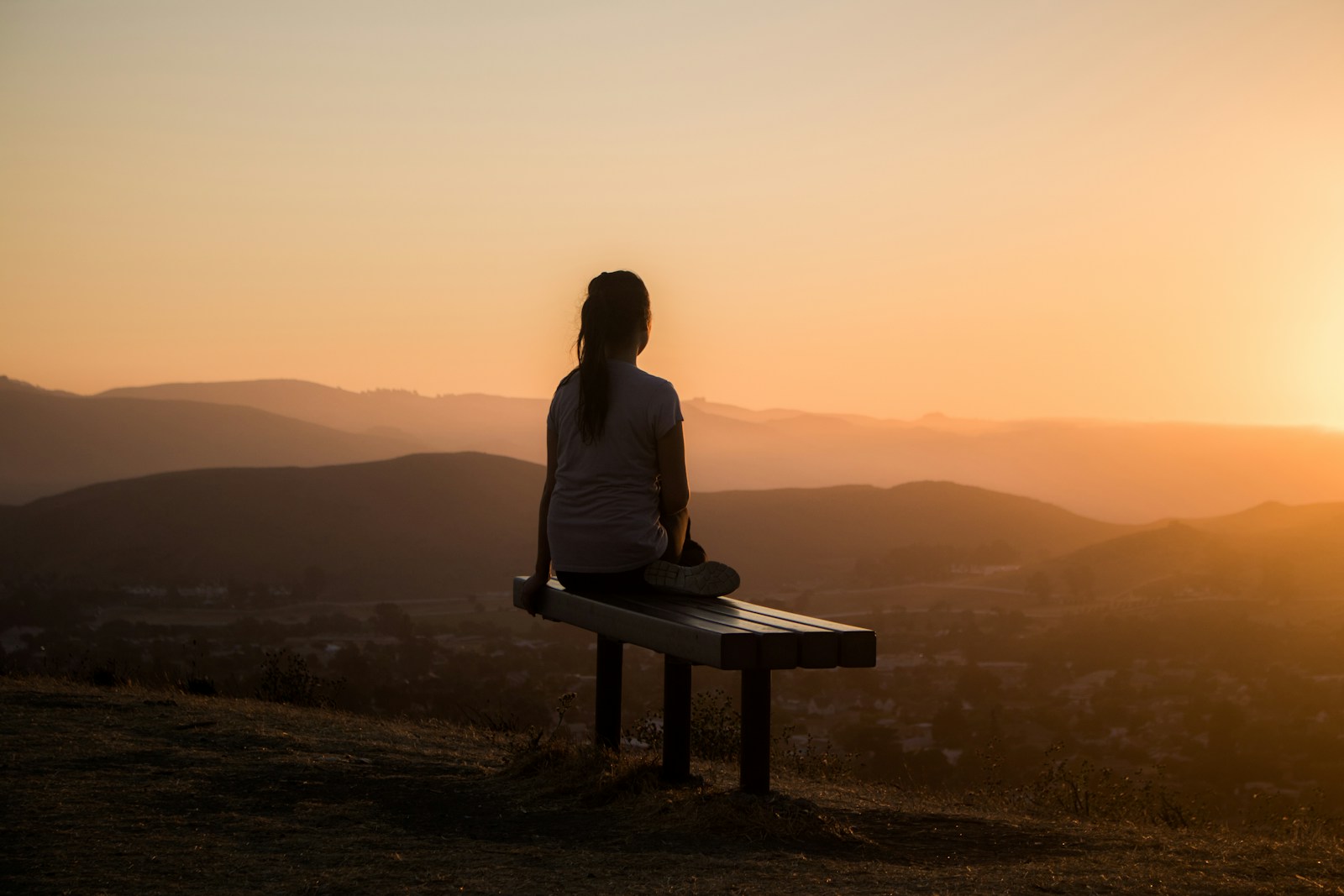woman sitting on bench over viewing mountain; Rituals