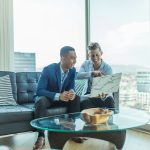 two men in suit sitting on sofa; scale as young entrepreneur