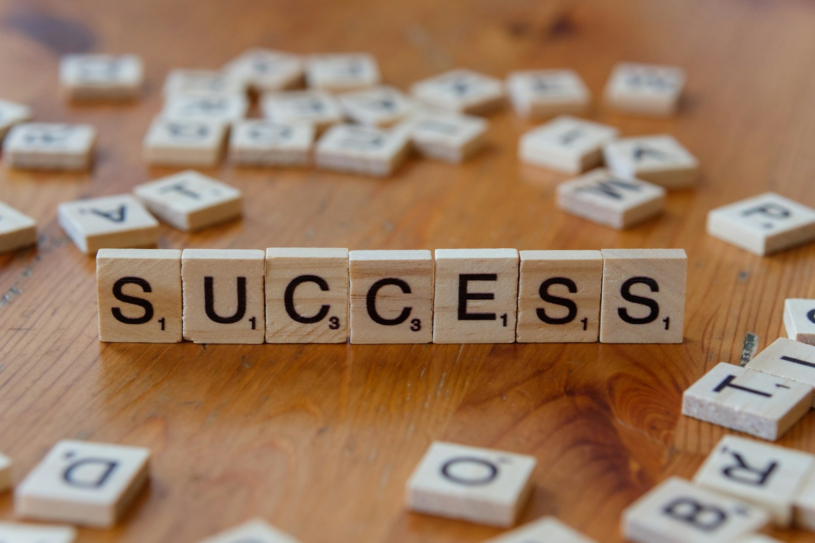 Scrabble tiles spelling out the word success on a wooden table; success feels emptier