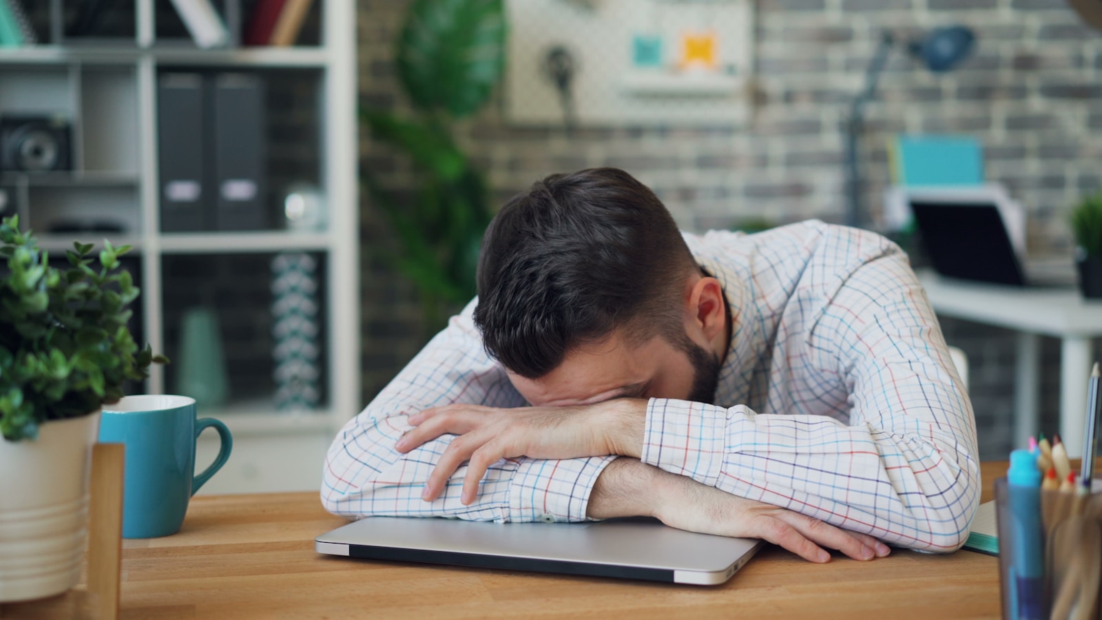 a man sitting at a desk with his head in his hands; ambition turns against you