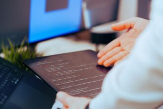 Software developer analyzing code on a tablet in a modern office workspace; small business AI