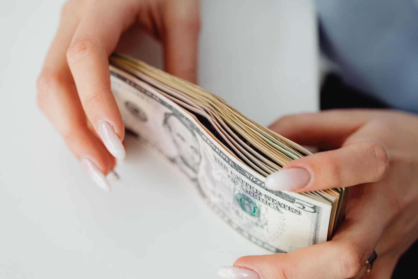 Hands carefully holding a stack of US dollar bills, representing finance and currency; median household income