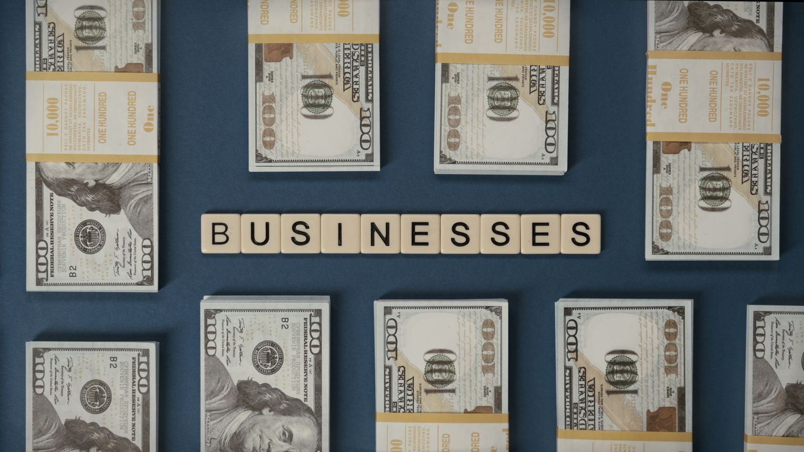 Bundles of US hundred-dollar bills and Scrabble tiles spelling