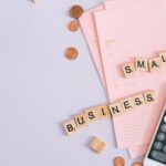 A top view image of small business tools including a calendar, coins, and a smartphone calculator; small business grants