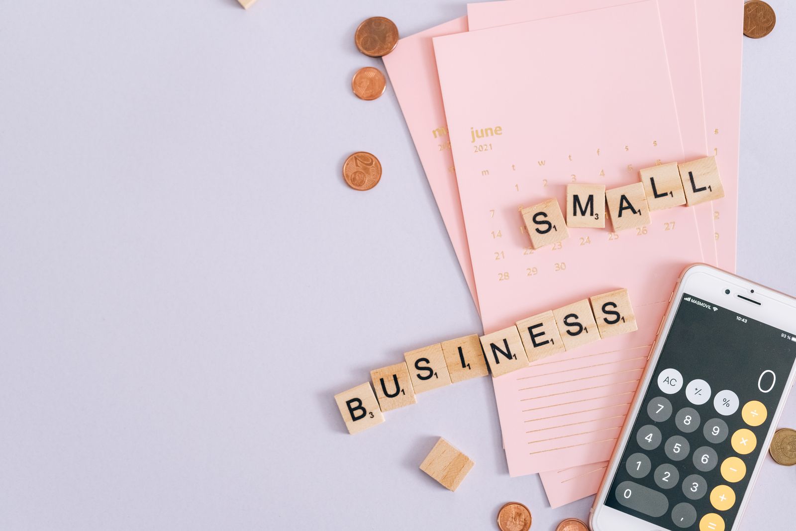 A top view image of small business tools including a calendar, coins, and a smartphone calculator; small business grants